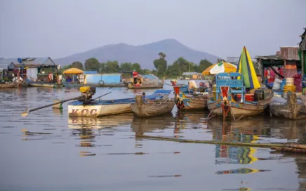 Colourful boats floating on a lake, with a mountain in the background