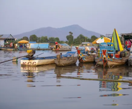 Colourful boats floating on a lake, with a mountain in the background