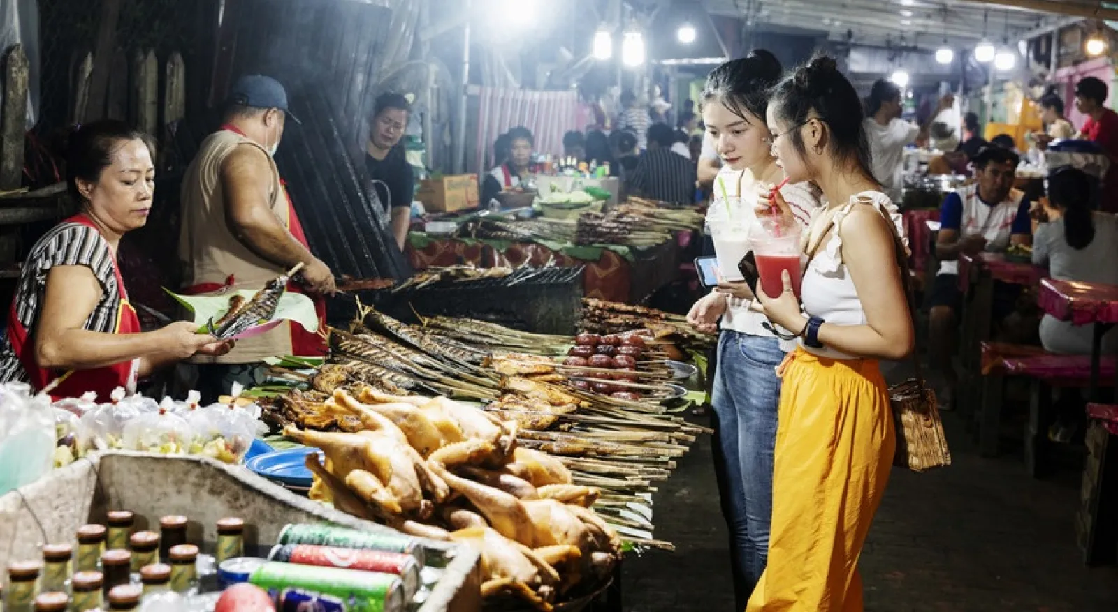 A busy street food market in Laos shows two people shopping for food