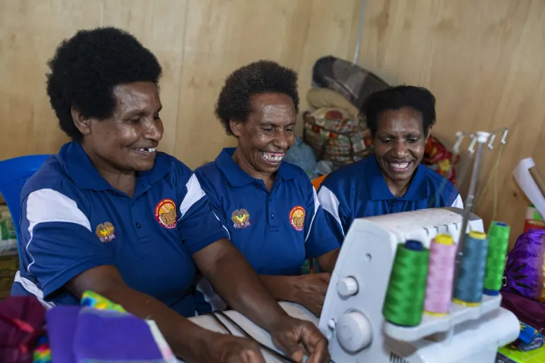 Three women working together on a sewing machine