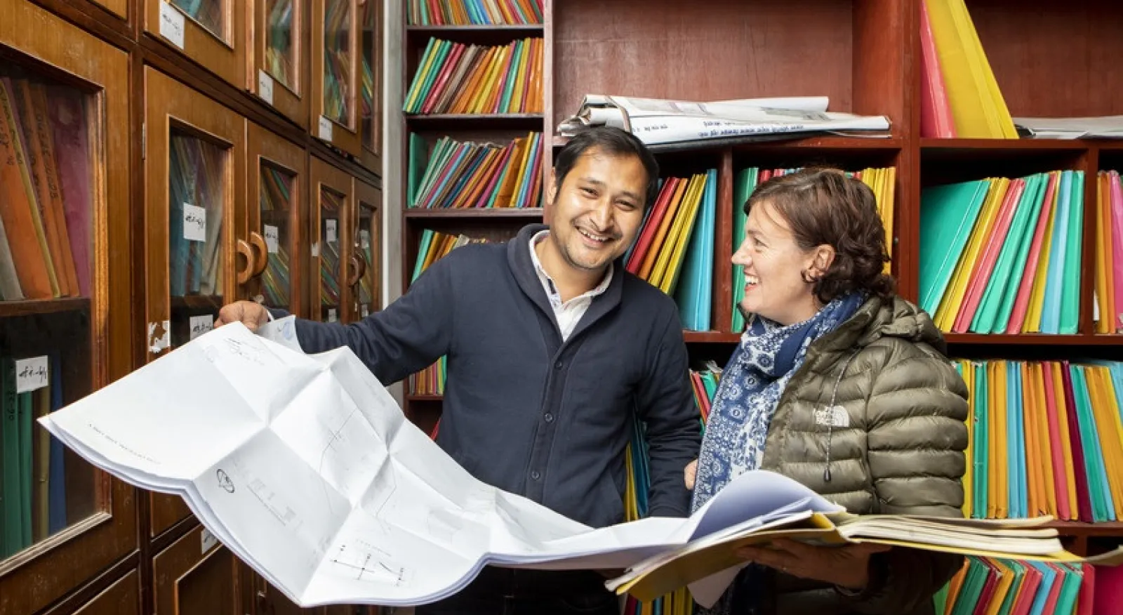 Two people in a library looking at a map. They are urban planners and researching the layout of Kathmandu, Nepal's capital.
