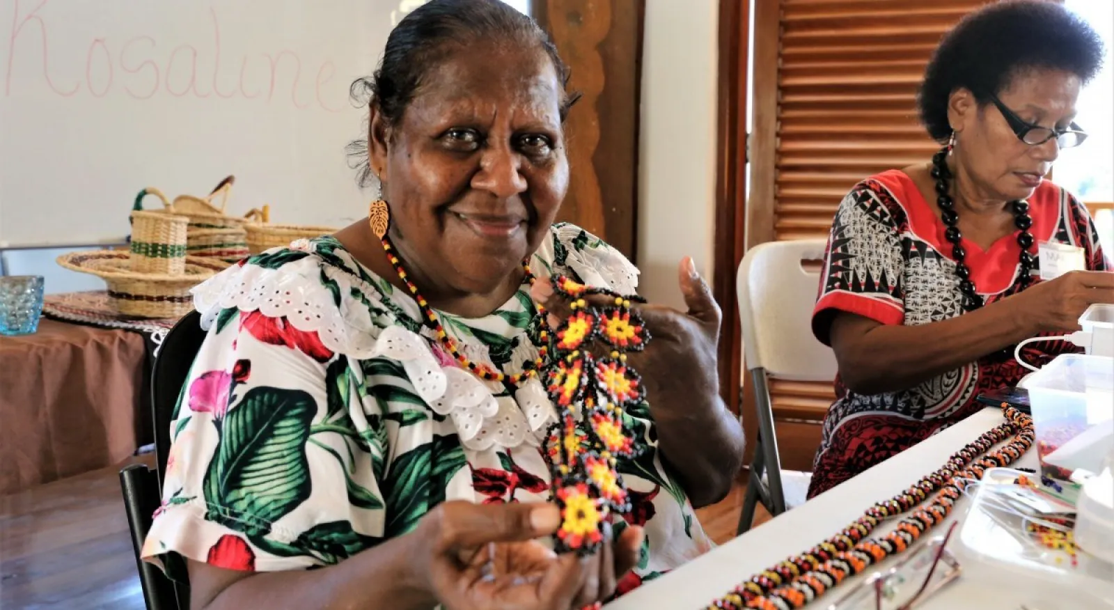 A person holds up a handmade beaded necklace.