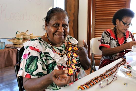 A person holds up a handmade beaded necklace.