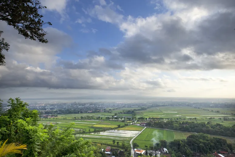 A beautiful view of green fields, houses and clouds in a blue sky
