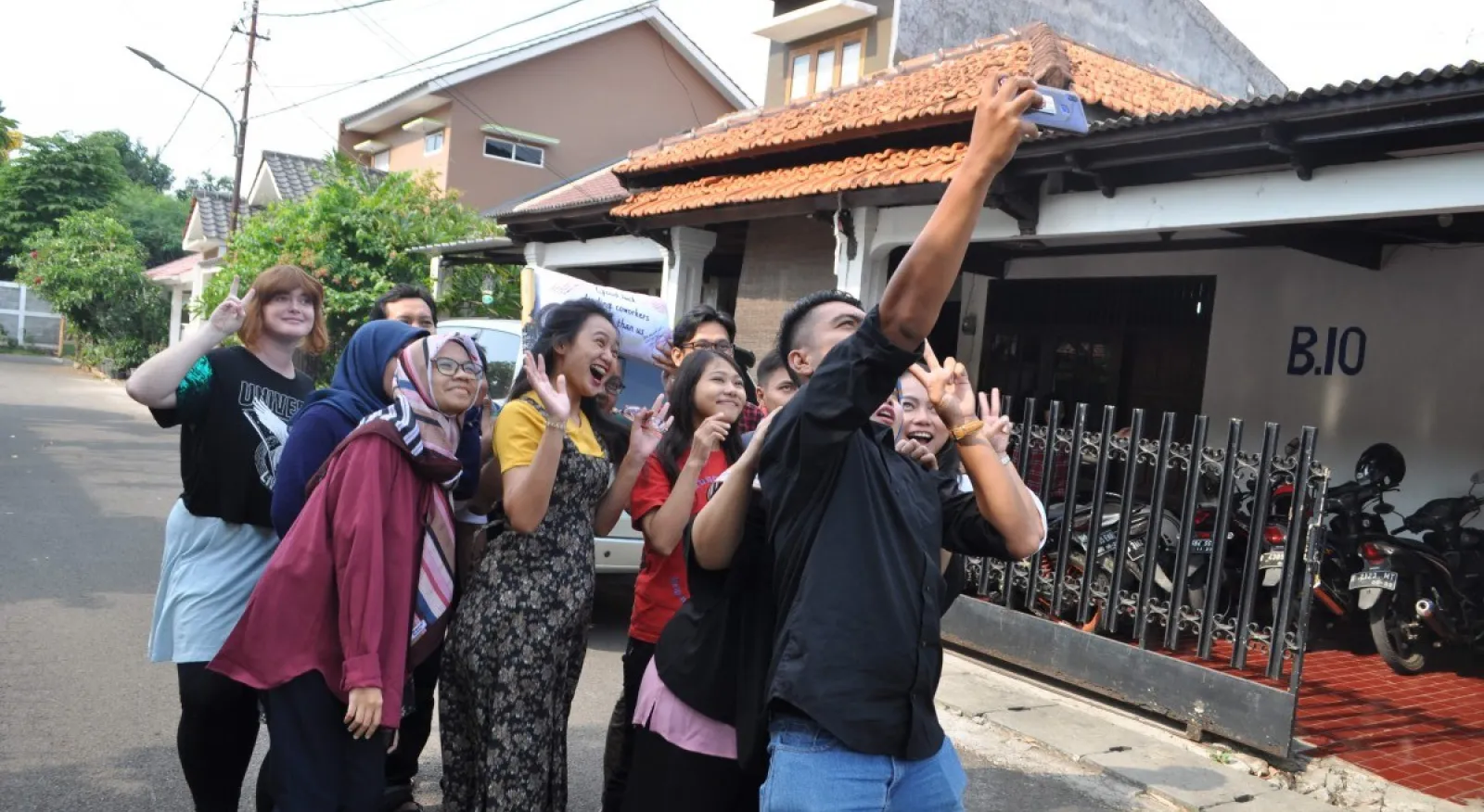 a group of people pose for a selfie in a suburban street setting.