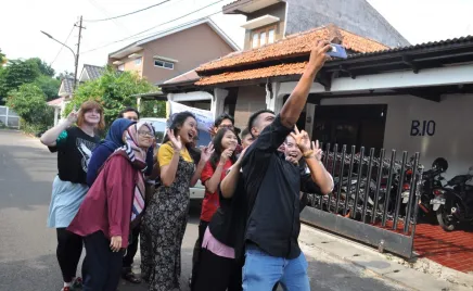 a group of people pose for a selfie in a suburban street setting.