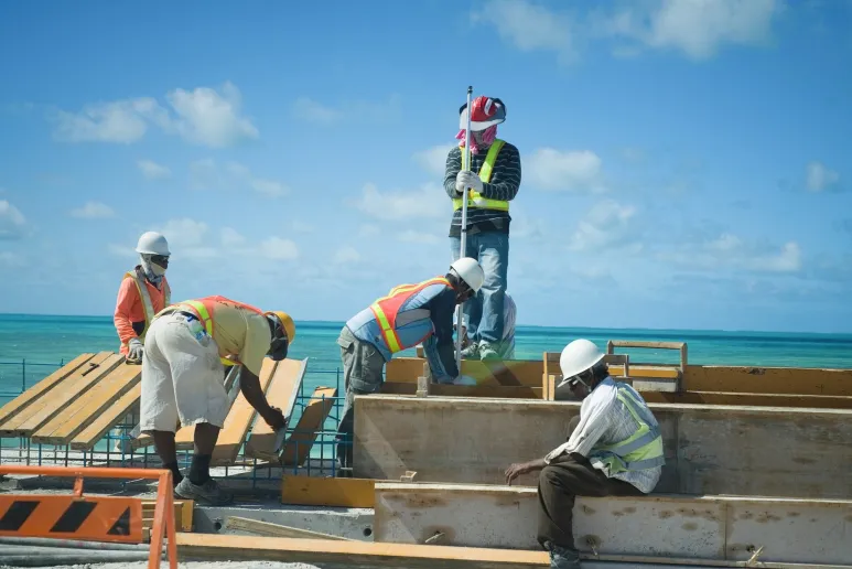Five people working on a construction site, with high vis vests and helmets.