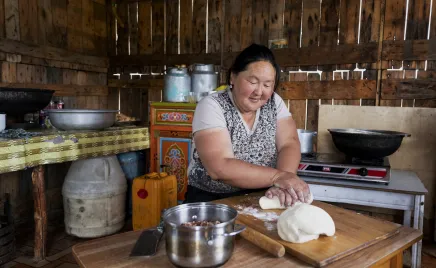 A person is rolling dough in a traditional Mongolian kitchen.