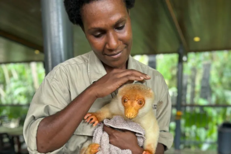 A women holding and patting a cuscus.