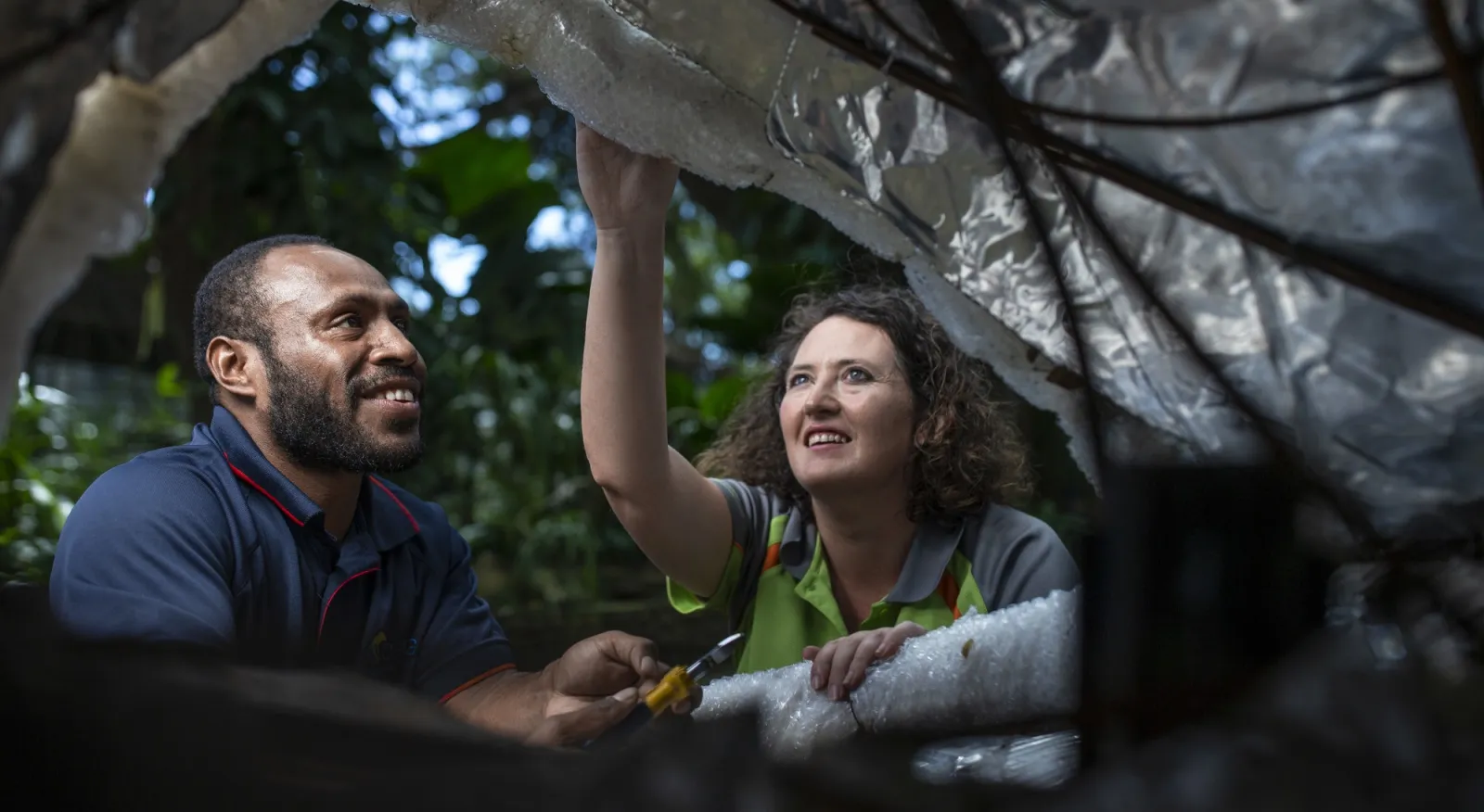 Two people looking inside a sculpture made form plastic and smiling.