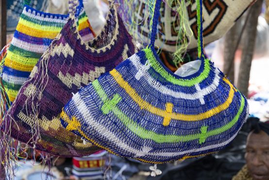 three colourful woven bags are hanging up