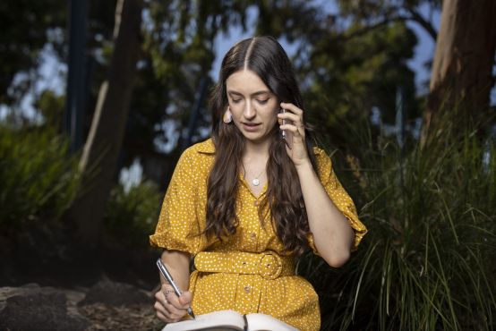 A women working on her compute while taking a call.