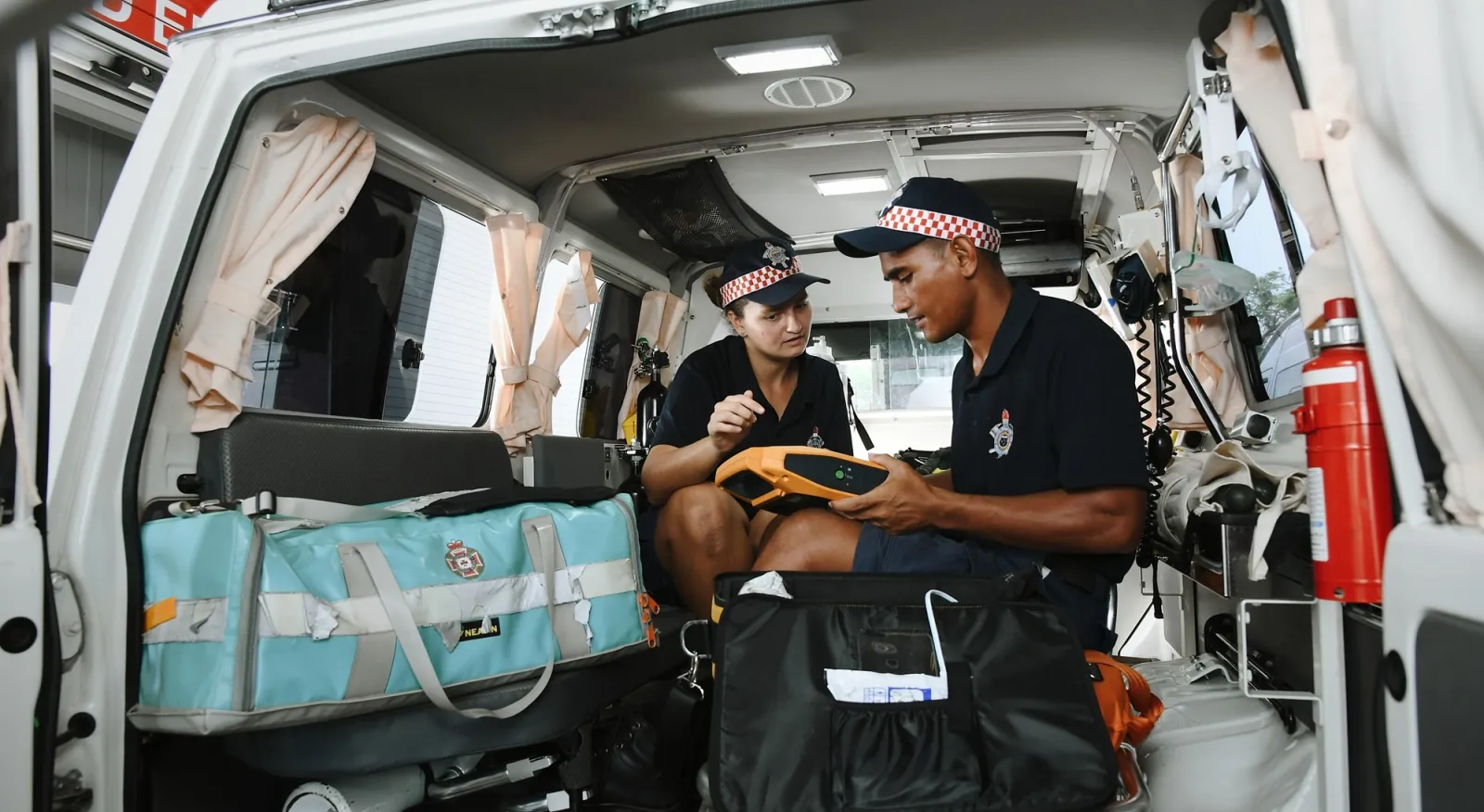 Two people sitting in the back of an ambulance, ready to provide medical assistance.