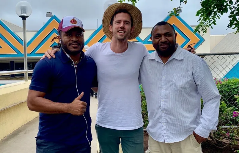Three men with arms around each other smiling at the camera.