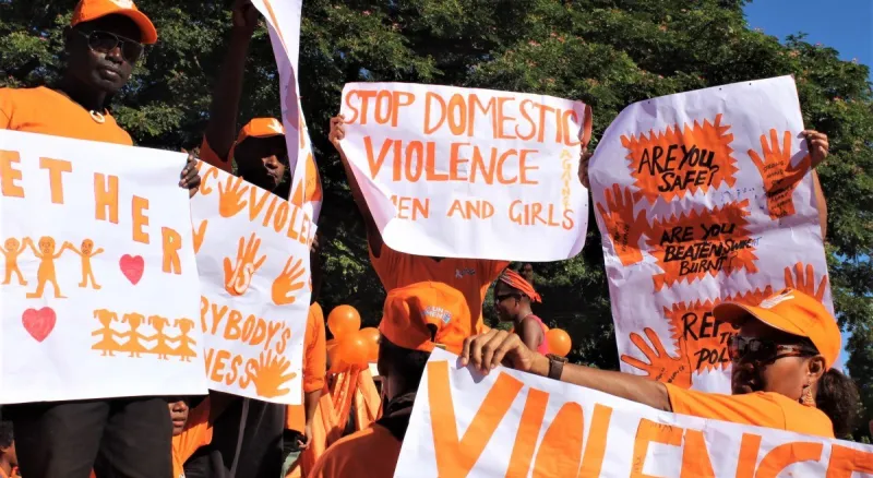 People wearing orange is a march holding signs against domestic violence