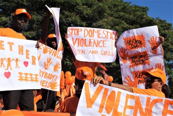 People wearing orange is a march holding signs against domestic violence