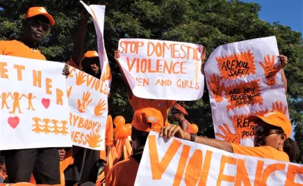 People wearing orange is a march holding signs against domestic violence