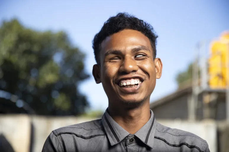 A profile photo of a man with short dark hair smiling, head tilted upwards.