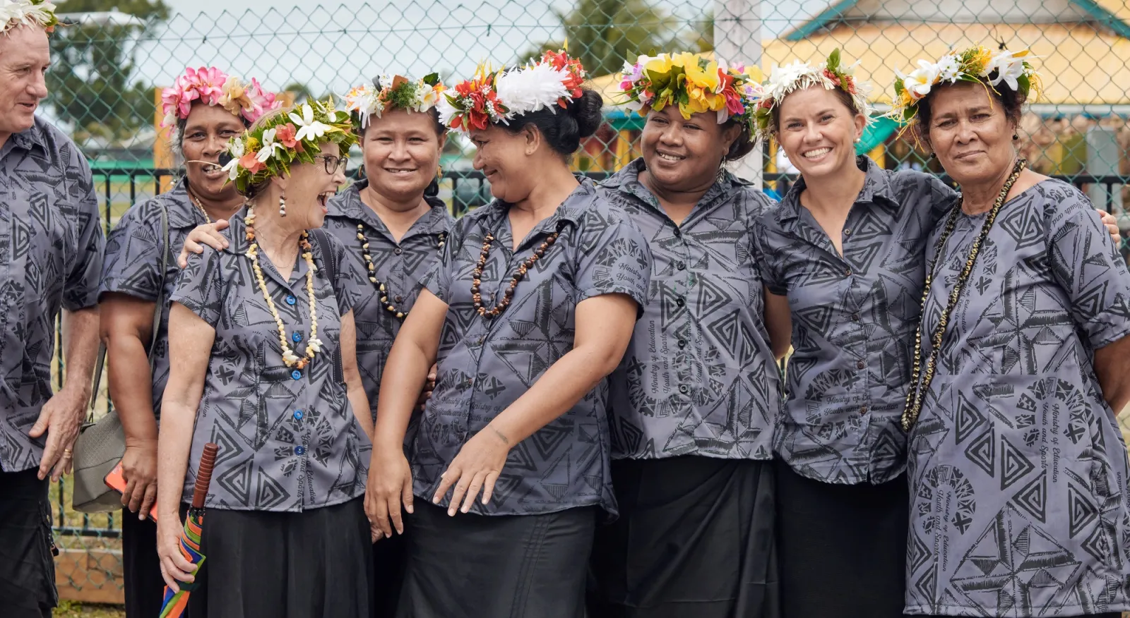A group of people in traditional attire and flower headwear posing for a photo.