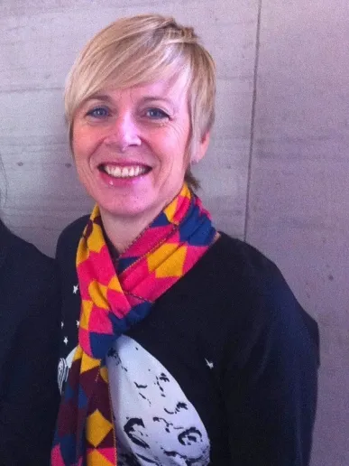 A woman with cropped blonde hair smiling at the camera
