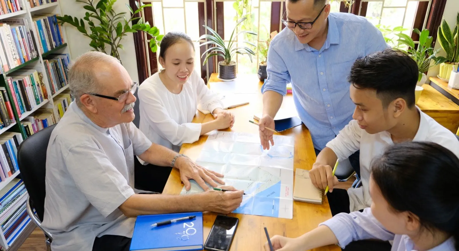 A group of people work together on a table in an office.