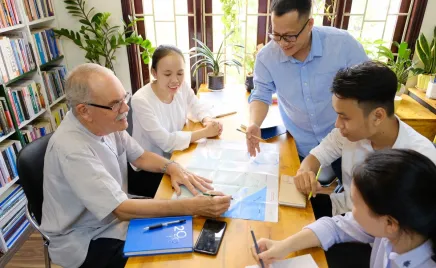 A group of people work together on a table in an office.